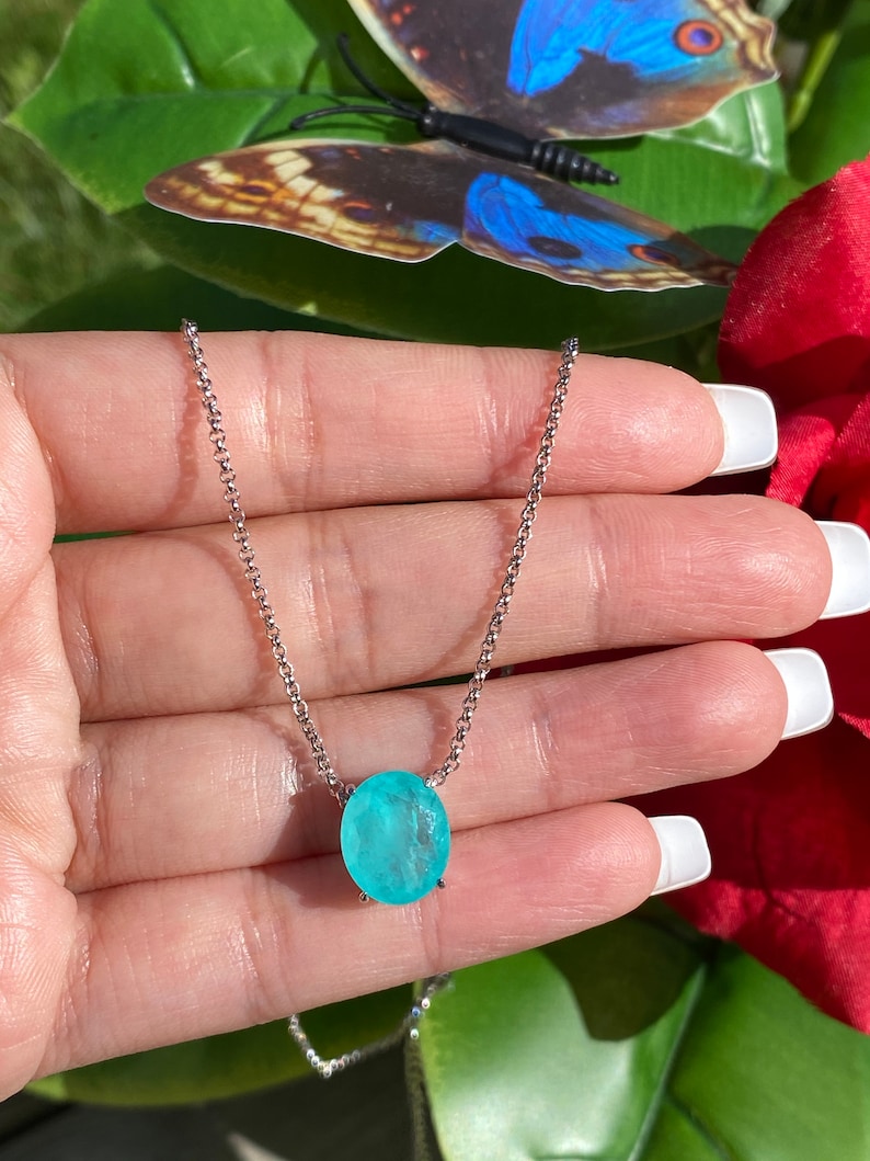 May include: A silver chain necklace with a light blue oval gemstone pendant.