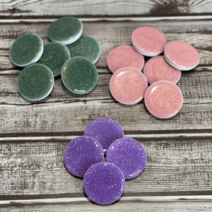 May include: Assortment of round, glittery phone grips in green, pink, and purple.