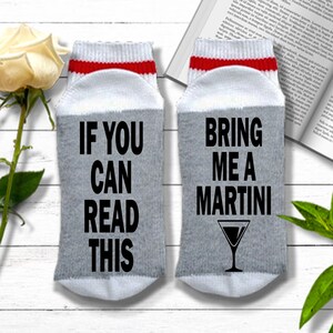 May include: A pair of gray and white socks with red trim. One sock says "If you can read this" and the other says "Bring me a martini" with a martini glass graphic.