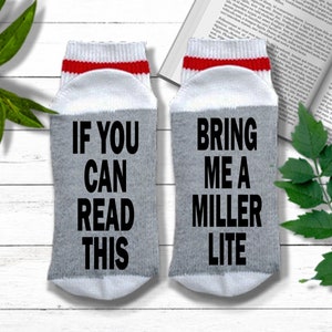 May include: A pair of gray socks with white and red trim. One sock says "If you can read this" and the other sock says "Bring me a Miller Lite".