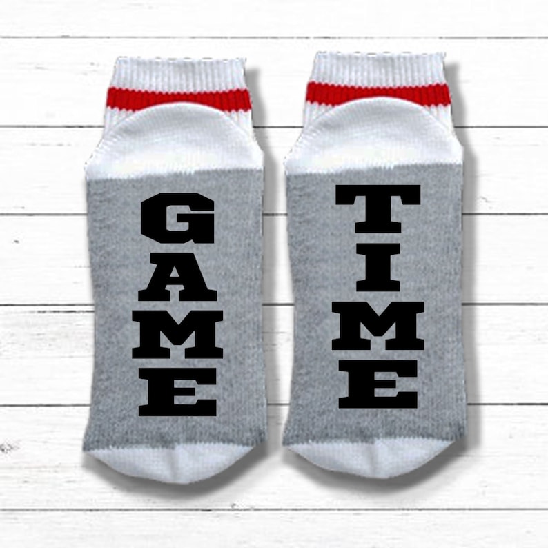 May include: A pair of gray and white socks with red stripes. One sock says "GAME" and the other says "TIME".