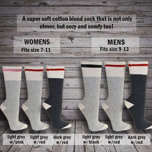 K&ouml;nnte beinhalten: Sechs Paar Socken aus Baumwollmischung mit verschiedenen farbigen Streifen am oberen Rand. Die Socken sind in zwei Reihen zu je drei angeordnet, wobei die obere Reihe mit "Womens" und die untere Reihe mit "Mens" beschriftet ist. Die Socken sind hellgrau mit entweder rosa, roten oder schwarzen Streifen und dunkelgrau mit roten Streifen.
