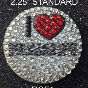 May include: A 2.25 inch round rhinestone-covered  'I Love NY'  charm with a red rhinestone heart. The charm is labeled 'RGF1' and is a standard size.