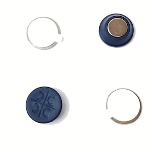 May include: Four round magnetic buttons, two black with a symbol and two black with a silver centre. Two silver rings are also included.