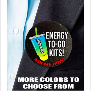 May include: A black and white button with a green, blue, and yellow Herbalife energy drink cup graphic. The button says "ENERGY TO-GO KITS! ASK ME HOW!" in white text.
