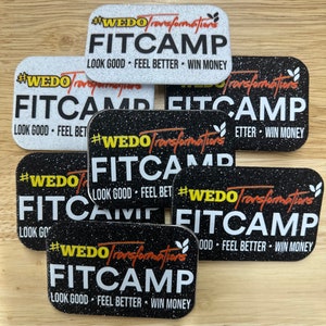 May include: Multiple black and white stickers with glitter and orange text that reads "#WEDO Transformations FITCAMP LOOK GOOD FEEL BETTER WIN MONEY".