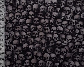 Puede incluir: Una tela negra con un patrón denso y repetitivo de cráneos humanos realistas en tonos grises y blancos. Una regla blanca con marcas negras es visible en los bordes izquierdo e inferior, midiendo hasta 38 cm y 30 cm.