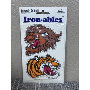 May include: A package of "Iron-ables" iron-on patches featuring a lion and a tiger. The lion is brown and orange with a red mouth. The tiger is orange and black with a red mouth. The package has the text "Scratch & Sniff".