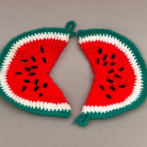 May include: Two crocheted watermelon pot holders, each with a green outer edge, a white middle band, and a red watermelon slice with black seeds in the center.