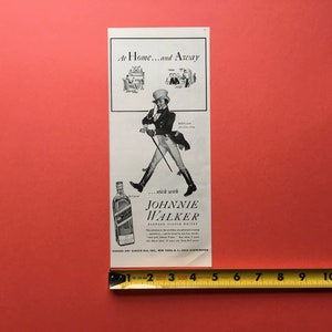 Puede incluir: Un anuncio vintage en blanco y negro para Johnnie Walker Scotch Whisky. El anuncio presenta a un hombre con un sombrero de copa y un bast&oacute;n, con una botella de Johnnie Walker en primer plano. El texto dice "At Home...and Away...stick with Johnnie Walker Scotch Whisky".