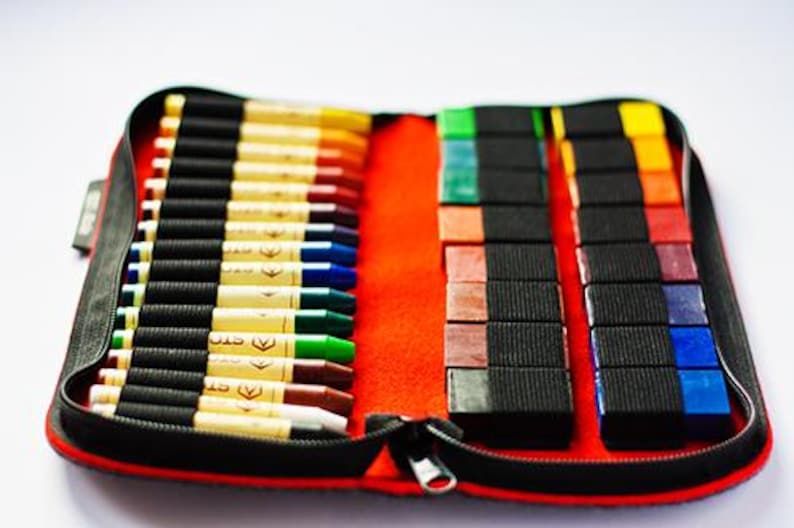 May include: A red zippered case with a black interior holds a set of 30 crayons. The crayons are arranged in two rows, with the first row containing 15 crayons and the second row containing 15 crayons. The crayons are all different colors, including red, orange, yellow, green, blue, purple, and brown.