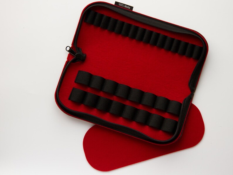 May include: Red felt zippered case with black elastic loops for holding small items. The case is open and the inside is lined with black felt. The case has a label that says "100% Woolen".