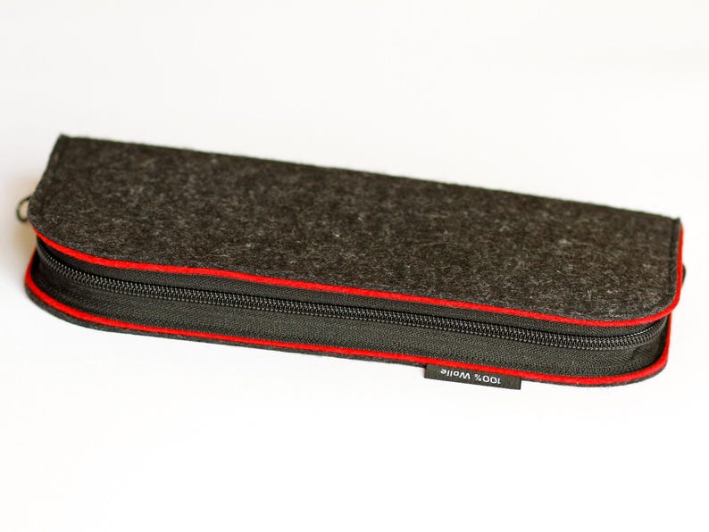 May include: A black felt pencil case with a red zipper and the text "100% WOOL" on the bottom.