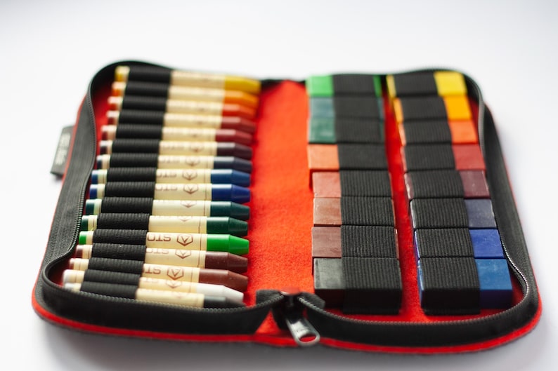 May include: A red zippered case with a black zipper pull holds a set of 24 crayons. The crayons are arranged in two rows, with 12 crayons in each row. The crayons are a variety of colors, including red, orange, yellow, green, blue, purple, and brown. The case is made of a durable material and is perfect for storing and transporting crayons.