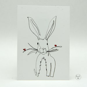 May include: A black and white line drawing of a rabbit with two small red hearts on its nose. The drawing is on a white card with the words "Amanda Art" in the bottom right corner.