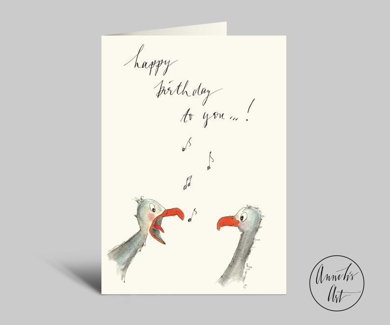 May include: A greeting card with a watercolor illustration of two birds singing. The card says "happy birthday to you..." with musical notes above the birds.