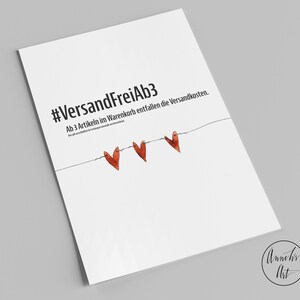 May include: White card with the text "#VersandFreiAb3 Ab 3 Artikeln im Warenkorb entfallen die Versandkosten." and three red hearts hanging on a string.
