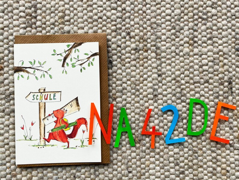 May include: A card with a cartoon squirrel carrying a ruler and a pencil, walking towards a sign that says "Schule" (German for school). The card is surrounded by colorful letters that spell out "NA42DE".