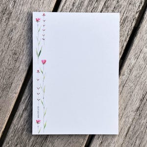 Könnte beinhalten: Eine weiße Karte mit einer Aquarell-Illustration von rosa Blüten und grünen Stielen am linken Rand. Der Text "www.studio-of-life.de" ist unten auf der Karte gedruckt.