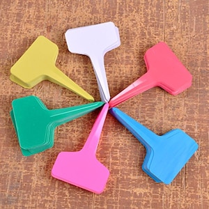 May include: Six plant markers in different colors, including green, pink, blue, yellow, white, and red. The markers are made of plastic and have a pointed end for inserting into the soil.