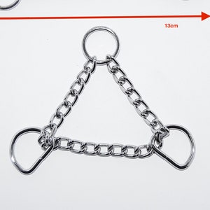 Könnte beinhalten: Zwei Edelstahl-Ketten-Leinenbefestigungen. Eine ist eine gerade Kette mit einem Ring an einem Ende und einem D-Ring am anderen. Die andere ist eine dreieckige Kette mit Ringen und D-Ringen. Die gerade Kette ist 13 cm lang.