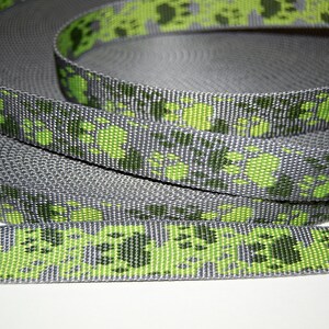 Puede incluir: Cinta gris y verde con un patr&oacute;n de huellas de patas. La cinta est&aacute; enrollada y las huellas de patas son visibles en la parte superior e inferior del rollo.