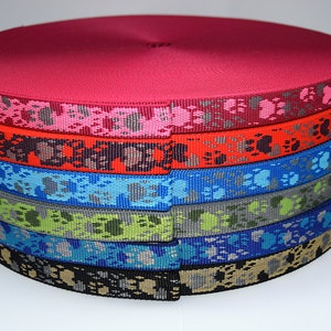 Puede incluir: Un rollo de cinta de colores con un patr&oacute;n de huella de pata. La cinta es roja, rosa, naranja, azul, verde, azul verdoso y negra.