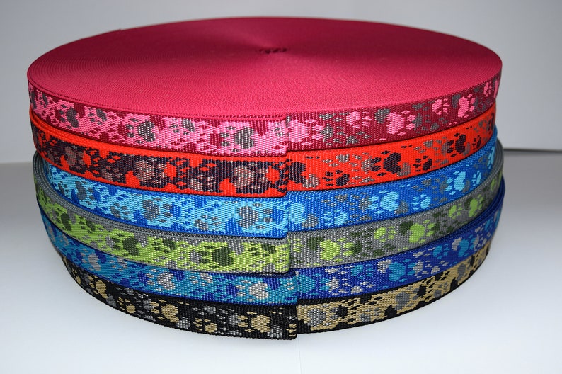 Puede incluir: Un rollo de cinta de colores con un patr&oacute;n de huella de pata. La cinta es roja, rosa, naranja, azul, verde, azul verdoso y negra.