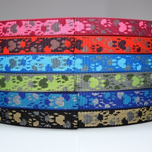 Puede incluir: Una pila de seis cintas de correa para perros de diferentes colores con un patr&oacute;n de huella de pata. Los colores son rosa, rojo, azul, verde, azul claro y negro.