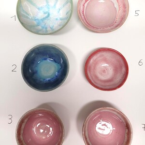 Könnte beinhalten: Sechs Keramikschalen in zwei Spalten angeordnet, nummeriert mit 1, 2, 3, 5, 6 und 7. Schale 1 hat ein blau-weißes Blumenmuster. Schale 2 ist tiefblau. Die Schalen 3, 5, 6 und 7 zeigen verschiedene Rosatöne, von blass bis kräftig, mit glasierten Oberflächen.