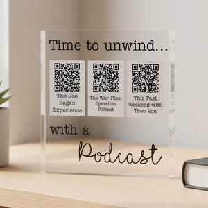 Könnte beinhalten: Ein transparenter Acrylblock mit dem schwarz aufgedruckten Text Time to unwind... with a Podcast und drei QR-Codes mit den Beschriftungen The Joe Rogan Experience, The Why Files: Operation Podcast und This Past Weekend with Theo Von.