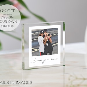 May include: A clear glass photo cube with a picture of two people smiling and hugging. The text "Love you, mom" is written in black cursive on the bottom of the photo.