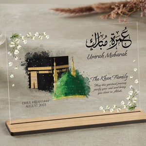 Clear plaque with wooden stand for Umrah Mubarak gift. Printed with Islamic quote with personalised family name and quote with dates. Bestseller for Eid mubarak gifts and Muslim gifts for couples and families.