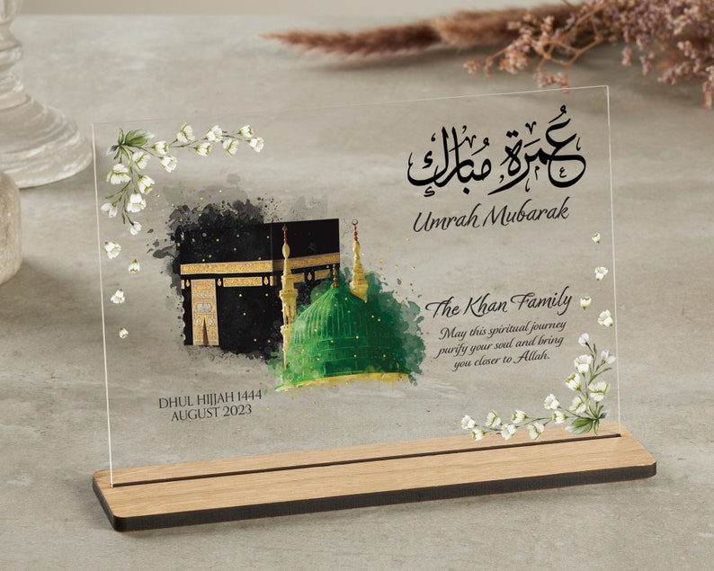 Clear plaque with wooden stand for Umrah Mubarak gift. Printed with Islamic quote with personalised family name and quote with dates. Bestseller for Eid mubarak gifts and Muslim gifts for couples and families.