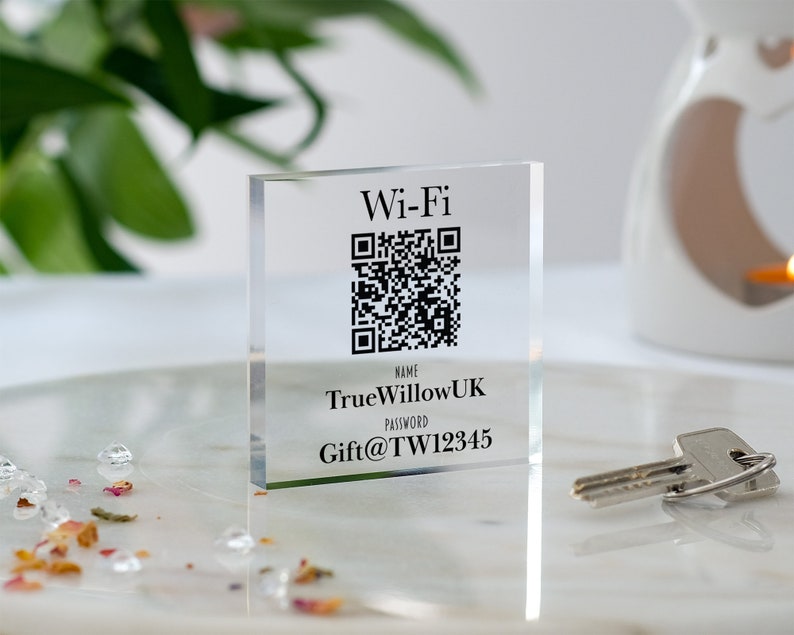 以下が含まれることがあります： 白地に黒と白のQRコード、テキスト「Wi-Fi」、「NAME: TrueWillowUK」、「PASSWORD: Gift@TW12345」が書かれた透明なアクリルブロックです。