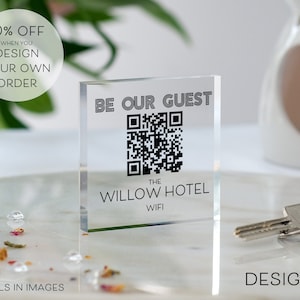 Könnte beinhalten: Ein klares Acrylschild mit dem Text "Be Our Guest" und einem schwarz-weißen QR-Code. Unter dem QR-Code befindet sich der Text "The Willow Hotel WiFi".