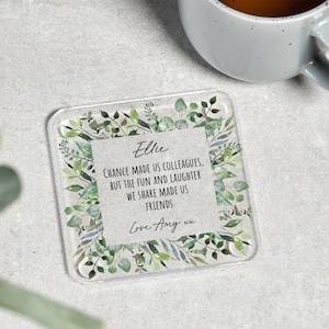 May include: A clear glass coaster with a green floral design and a personalized message that reads "Ellie CHANCE MADE US COLLEAGUES, BUT THE FUN AND LAUGHTER WE SHARE MADE US FRIENDS Love Amy xu".