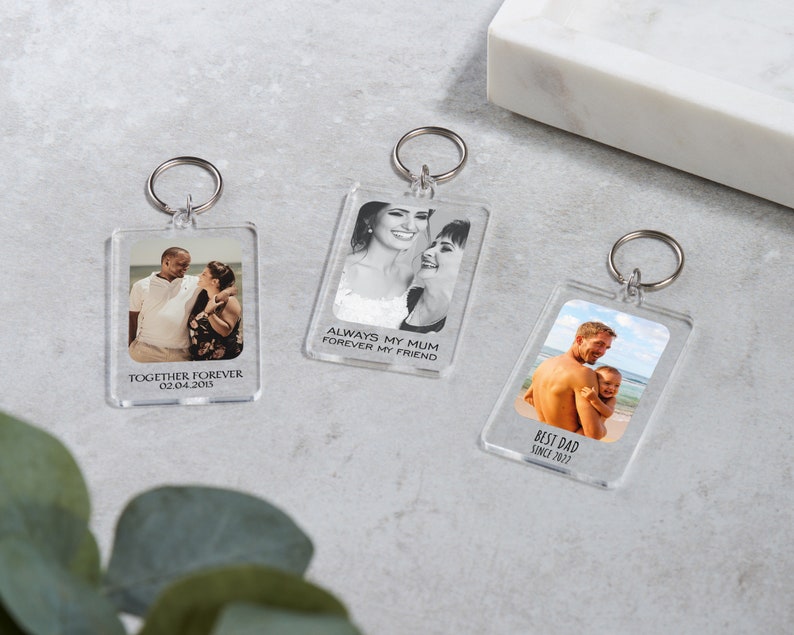 May include: Three clear acrylic keychains with photos and text. The first keychain has a photo of a couple and the text "Together Forever 02.04.2015". The second keychain has a photo of two women and the text "Always my Mum Forever my Friend". The third keychain has a photo of a father and child and the text "Best Dad Since 2022".