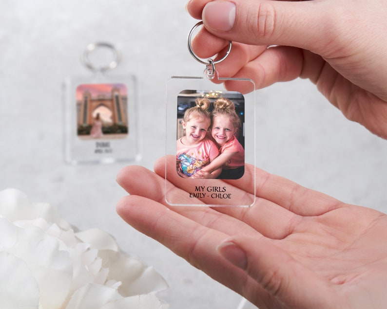 May include: A clear acrylic keychain with a photo of two young girls smiling. The text "MY GIRLS EMILY - CHLOE" is printed below the photo.