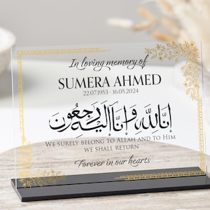 May include: A clear acrylic plaque with gold floral accents and black text. The plaque reads "In loving memory of SUMERA AHMED 22.07.1953 - 16.05.2024" and includes an Arabic inscription. The text below the inscription reads "WE SURELY BELONG TO ALLAH AND TO HIM WE SHALL RETURN Forever in our hearts."