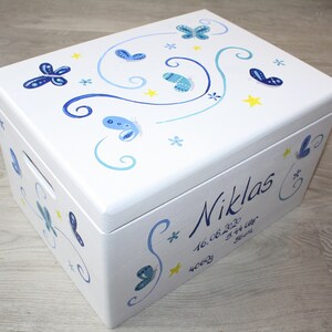 May include: White wooden keepsake box with a blue and yellow butterfly design. The box is personalized with the name "Niklas" and the date "16.08.2020".