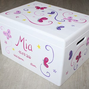 May include: White wooden storage box with a butterfly and star design. The box is painted with pink, purple, and yellow butterflies and stars. The name "Mia" is written in pink lettering on the front of the box, along with the date "15.09.2020".