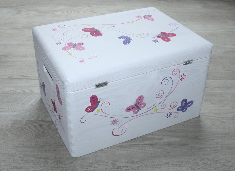 May include: White wooden storage chest with a butterfly design. The chest is decorated with pink, purple, and red butterflies on a white background.