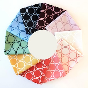 Könnte beinhalten: Ein Satz von zehn Stoffquadraten mit einem weißen Kreis-Muster auf verschiedenen farbigen Hintergründen, darunter Blau, Grün, Gelb, Orange, Rot, Rosa, Braun und Schwarz.