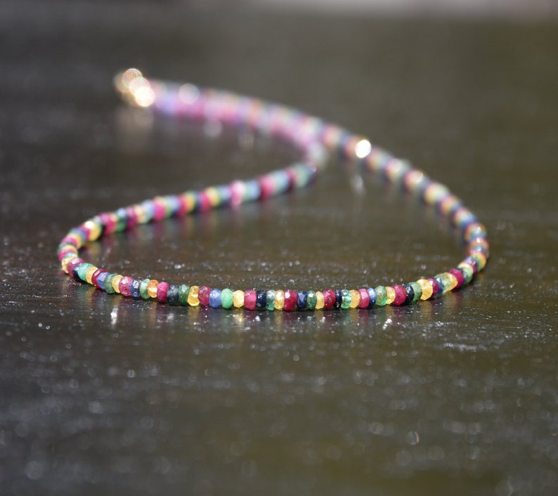 Pu&ograve; includere: Una delicata collana composta da piccole pietre preziose colorate. La collana presenta una variet&agrave; di colori, tra cui rosso, giallo, verde e blu, infilati insieme. La chiusura sembra essere dorata. Le pietre preziose sono uniformemente distanziate.