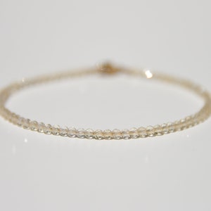 K&ouml;nnte beinhalten: Ein zartes Armband aus kleinen, klaren Perlen mit einem goldenen Verschluss.