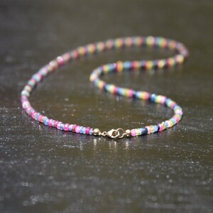 Pu&ograve; includere: Una collana colorata composta da piccole perline sfaccettate in una gamma di colori arcobaleno, tra cui rosa, blu, giallo e verde. La collana &egrave; assicurata con una chiusura dorata.