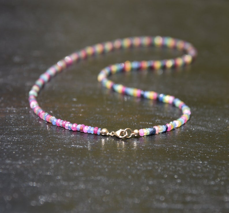 Pu&ograve; includere: Una collana colorata composta da piccole perline sfaccettate in una gamma di colori arcobaleno, tra cui rosa, blu, giallo e verde. La collana &egrave; assicurata con una chiusura dorata.