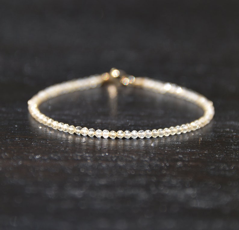 K&ouml;nnte beinhalten: Ein zartes Armband aus kleinen, klaren Perlen mit einem goldenen Verschluss.