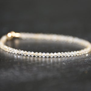 K&ouml;nnte beinhalten: Ein zartes Armband aus kleinen, klaren Perlen mit einem goldenen Verschluss.